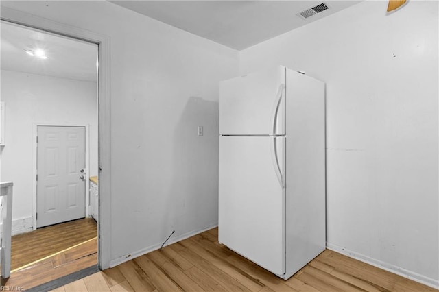 unfurnished bedroom with light wood-type flooring and white refrigerator