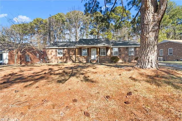 ranch-style home featuring covered porch and a front yard