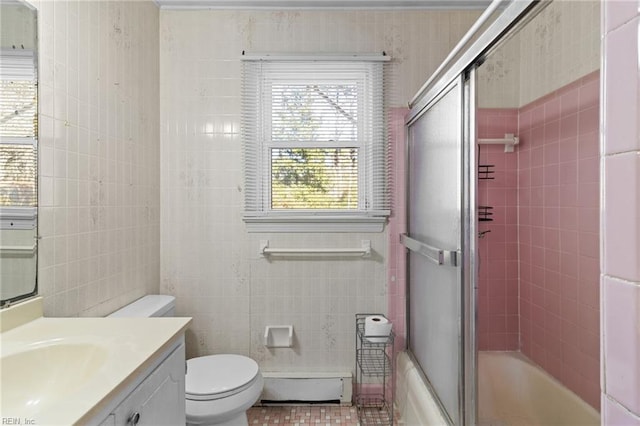 full bathroom featuring toilet, baseboard heating, tile walls, vanity, and shower / bath combination with glass door