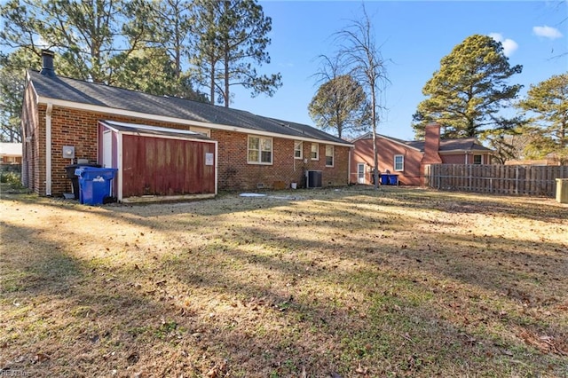 rear view of property featuring central AC unit, a storage unit, and a yard