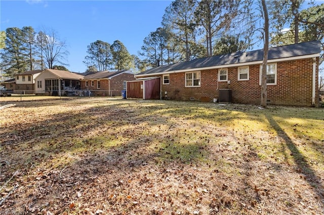 rear view of property with central air condition unit and a yard