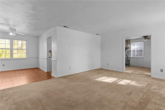 carpeted empty room with ceiling fan and a wealth of natural light