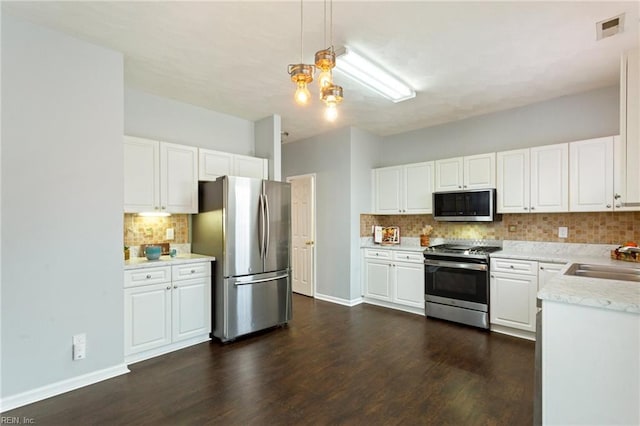 kitchen with decorative light fixtures, tasteful backsplash, sink, white cabinetry, and appliances with stainless steel finishes