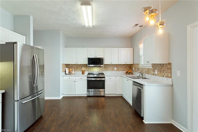 kitchen with stainless steel appliances, white cabinets, and hanging light fixtures