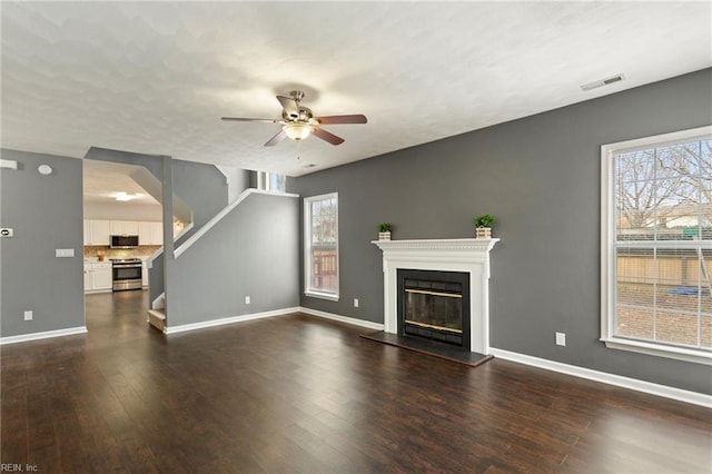 unfurnished living room with ceiling fan and dark wood-type flooring