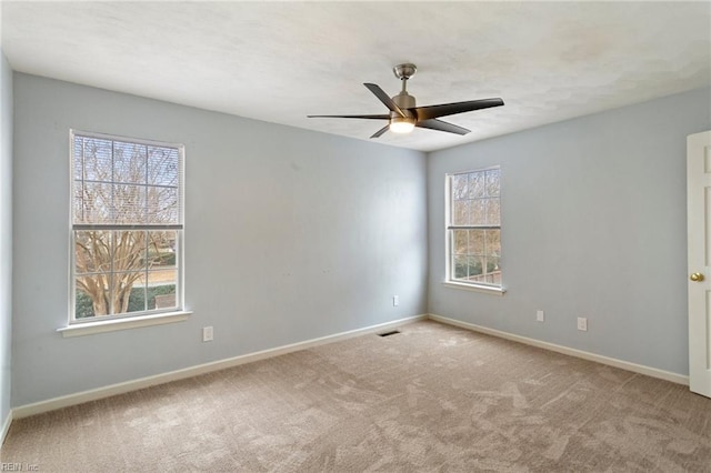 carpeted spare room featuring ceiling fan and plenty of natural light