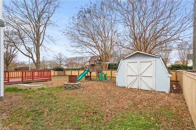 view of yard featuring a storage shed, a deck, and a playground