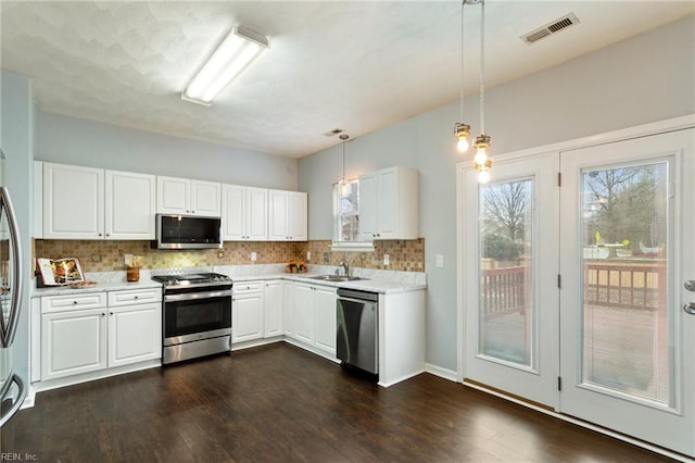 kitchen with white cabinetry, appliances with stainless steel finishes, backsplash, hanging light fixtures, and sink