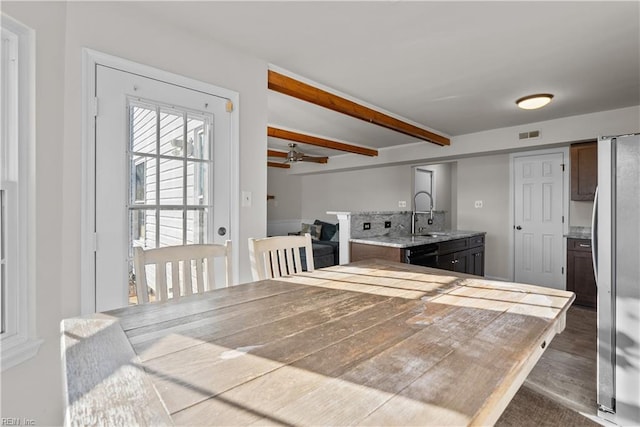 kitchen featuring ceiling fan, dark wood-type flooring, stainless steel refrigerator, beam ceiling, and sink