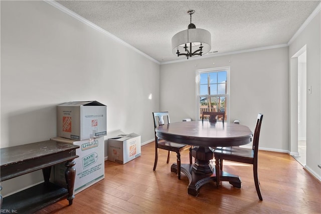 dining room featuring hardwood / wood-style flooring, a textured ceiling, ornamental molding, and a notable chandelier