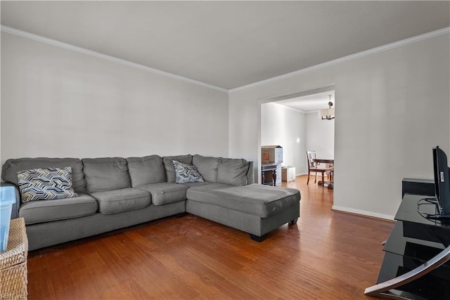 living room with wood-type flooring, a notable chandelier, and ornamental molding