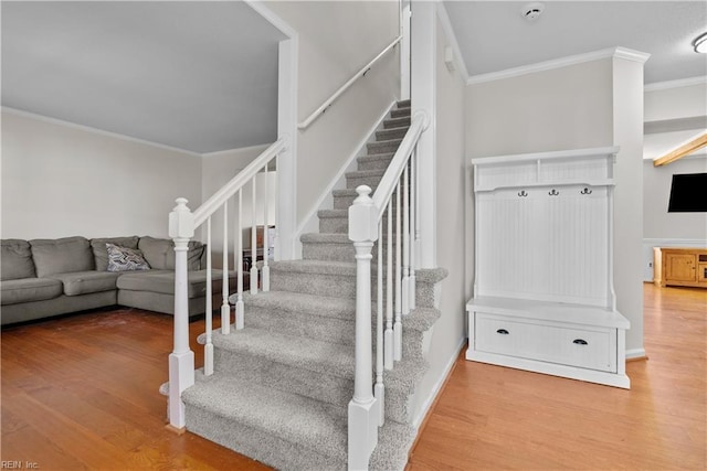 staircase with wood-type flooring and crown molding