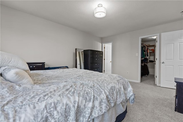 bedroom with light carpet, a closet, and a walk in closet