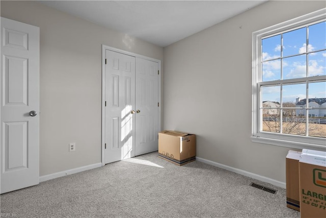 unfurnished bedroom with multiple windows, a closet, and light carpet