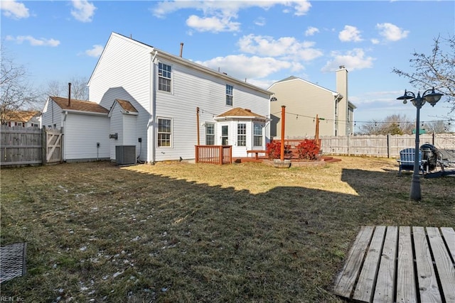 rear view of house featuring central AC unit, a deck, and a lawn