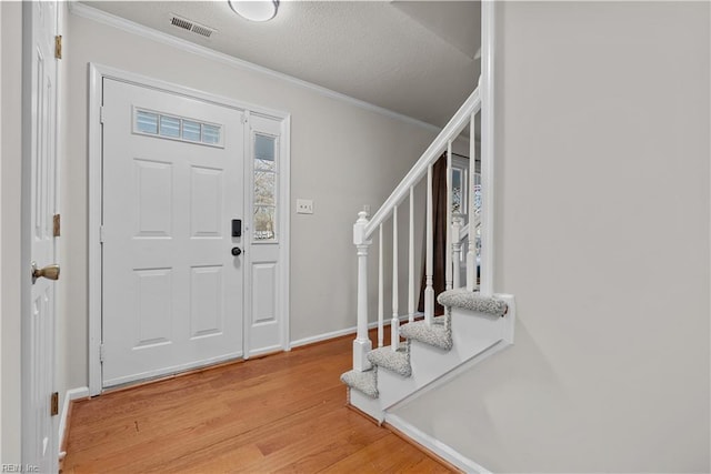 foyer with ornamental molding, a textured ceiling, and hardwood / wood-style flooring