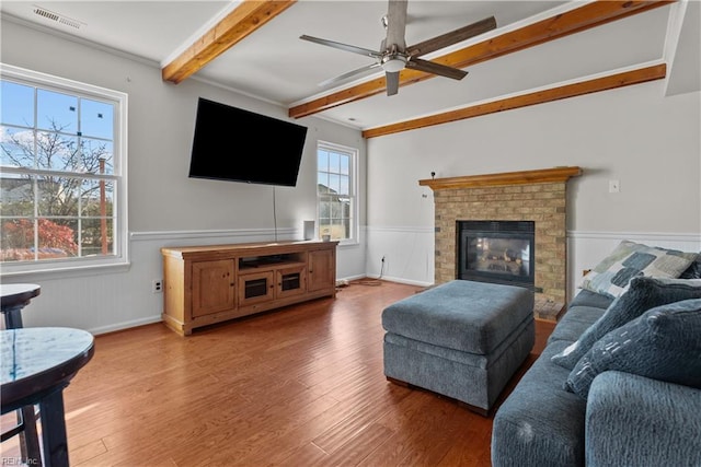 living room featuring ceiling fan, a fireplace, beamed ceiling, and hardwood / wood-style flooring