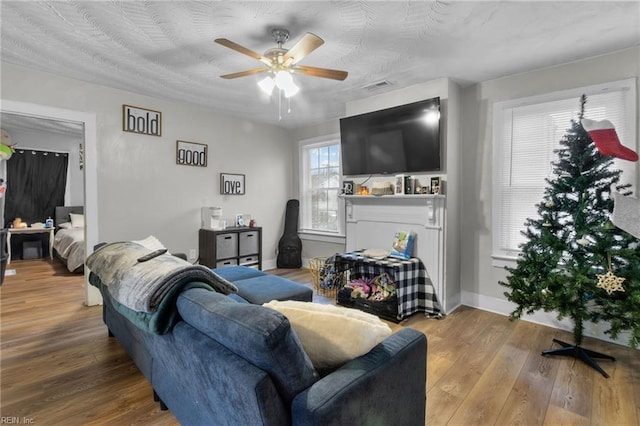 living room featuring ceiling fan, wood-type flooring, and a textured ceiling