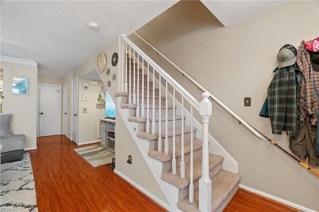 stairway with wood-type flooring and a textured ceiling