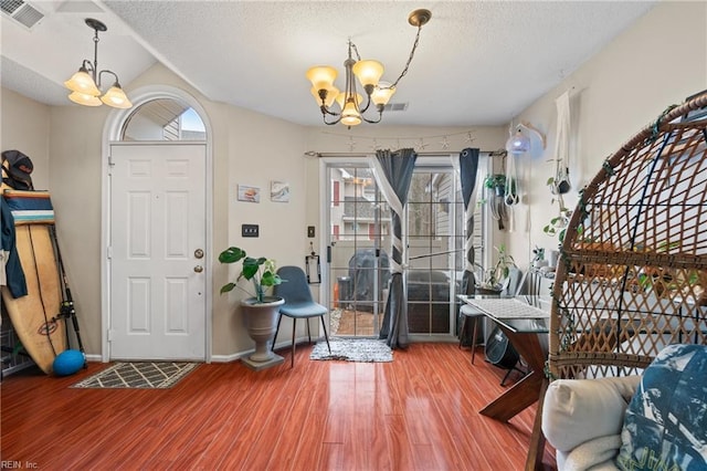 foyer entrance featuring a textured ceiling, hardwood / wood-style floors, and a notable chandelier