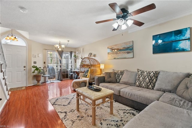 living room with crown molding, wood-type flooring, and ceiling fan with notable chandelier