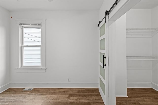 unfurnished room featuring dark hardwood / wood-style flooring and a barn door