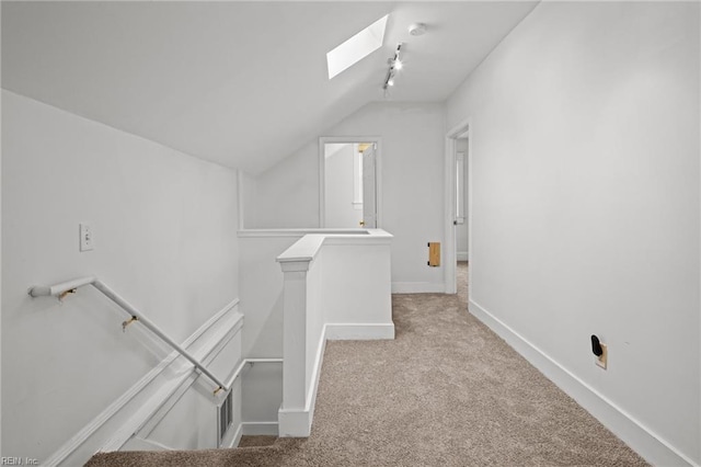 interior space featuring light carpet and vaulted ceiling with skylight