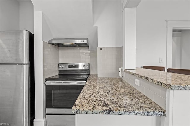 kitchen featuring tasteful backsplash, white cabinetry, light stone counters, appliances with stainless steel finishes, and wall chimney range hood