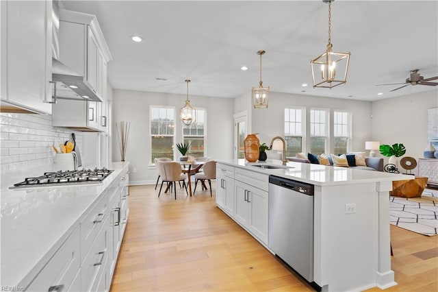 kitchen with appliances with stainless steel finishes, an island with sink, white cabinetry, and pendant lighting