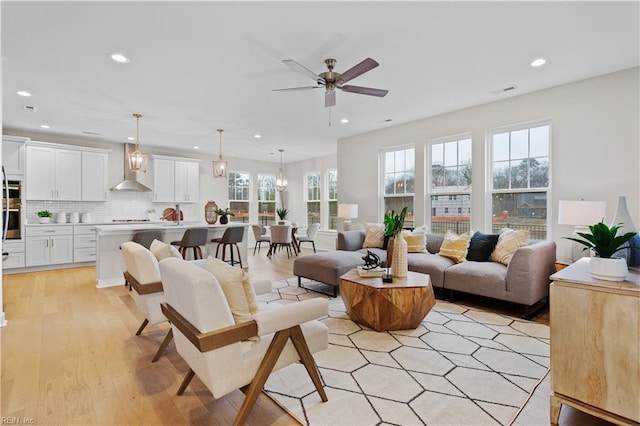 living room with ceiling fan, a wealth of natural light, and light hardwood / wood-style floors