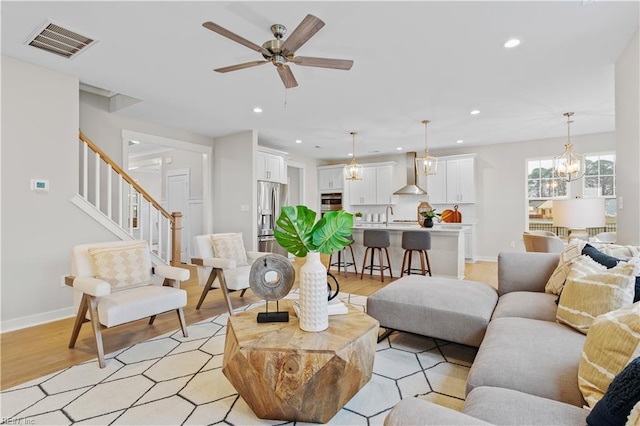 living room featuring ceiling fan with notable chandelier, light hardwood / wood-style flooring, and sink