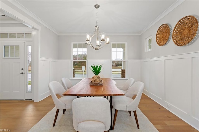 dining room with an inviting chandelier, ornamental molding, and light hardwood / wood-style flooring