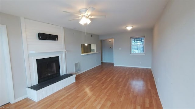 unfurnished living room featuring hardwood / wood-style flooring, a large fireplace, and ceiling fan