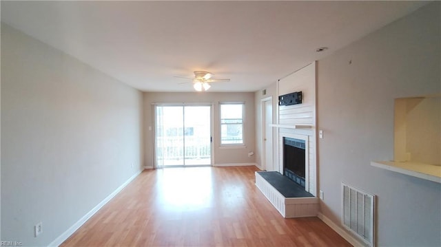 unfurnished living room featuring ceiling fan, a fireplace, and light hardwood / wood-style flooring