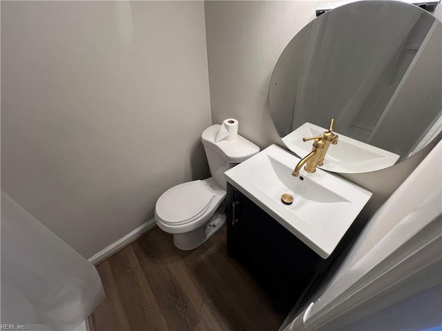 bathroom with toilet, vanity, and wood-type flooring