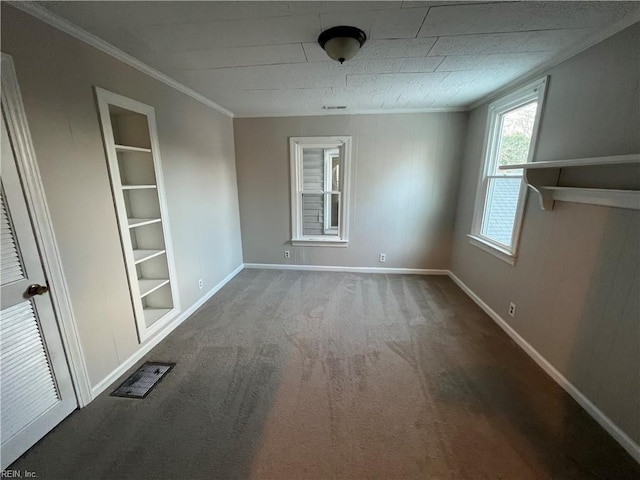 carpeted spare room with built in shelves and ornamental molding