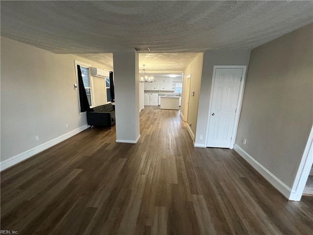 interior space with dark wood-type flooring, a textured ceiling, a wall mounted AC, and a notable chandelier