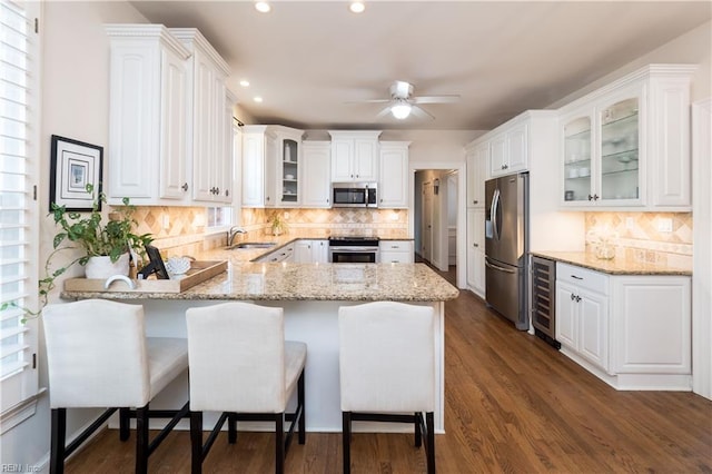 kitchen with stainless steel appliances, kitchen peninsula, and white cabinets