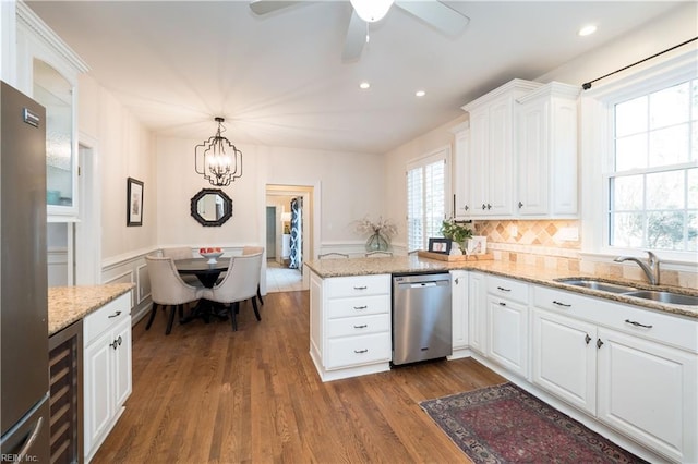 kitchen featuring sink, white cabinetry, decorative light fixtures, kitchen peninsula, and stainless steel appliances