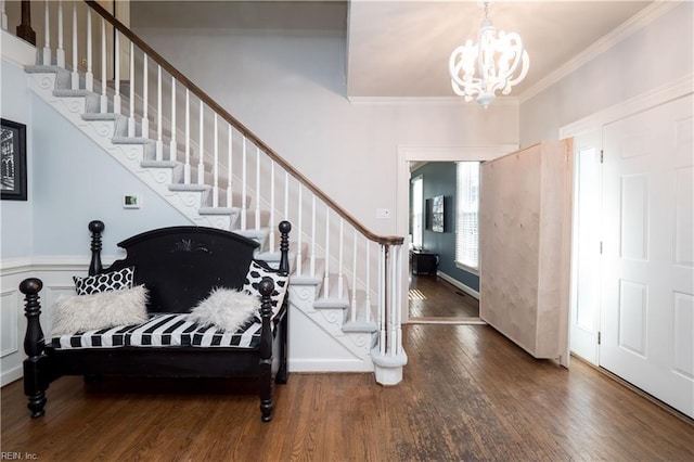 foyer entrance with dark wood-type flooring, crown molding, and a chandelier