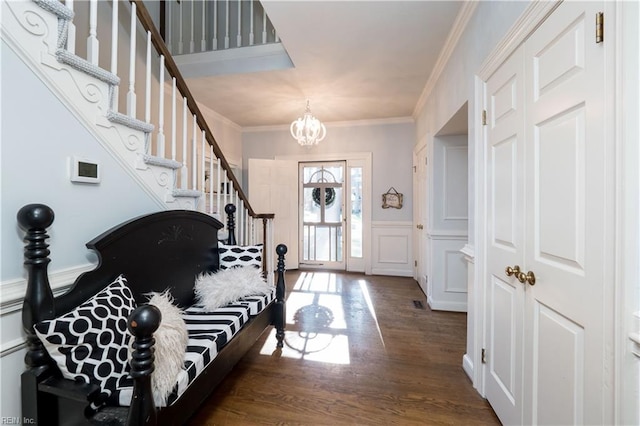 foyer entrance featuring a notable chandelier, ornamental molding, and dark hardwood / wood-style floors