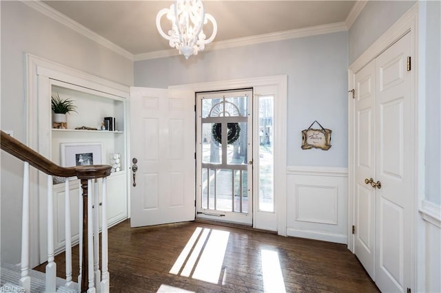 foyer entrance with an inviting chandelier, crown molding, and dark hardwood / wood-style floors