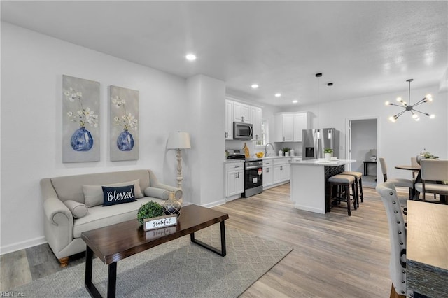 living room with a chandelier, light hardwood / wood-style floors, and sink