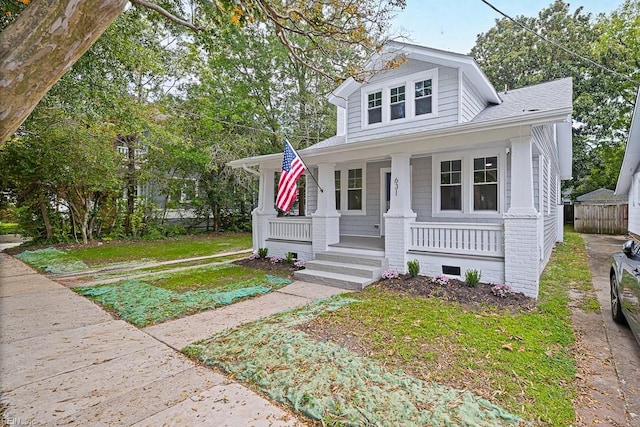 bungalow-style house featuring covered porch and a front yard