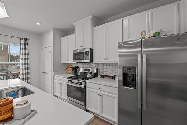 kitchen with stainless steel appliances, backsplash, white cabinets, and sink