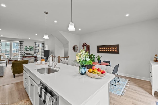 kitchen with an island with sink, dishwasher, hanging light fixtures, white cabinets, and sink