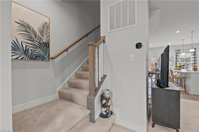 stairs with carpet flooring and sink