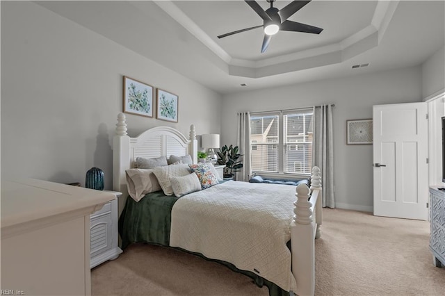 carpeted bedroom with a raised ceiling and ceiling fan