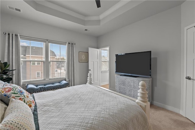 bedroom with ceiling fan, light colored carpet, and a tray ceiling