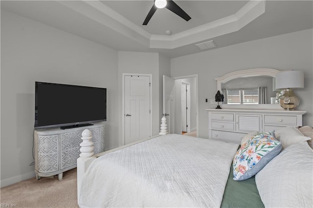 carpeted bedroom with ceiling fan and a tray ceiling